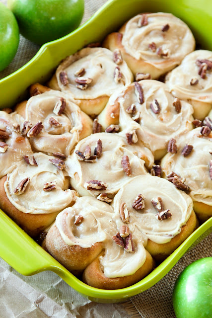 A 9x13 dish full of cinnamon apple rolls topped with pecans