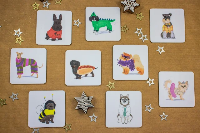 9 coasters with different dog illustrations on including a pug in a bee suit, husky in a suit, a sausage doll in a roll and springer spaniel in a dragon costume.