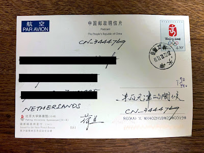 Achterkant van Chinese ansichtkaart met zwartgelakt adres links en handgeschreven Chinese tekst rechts
