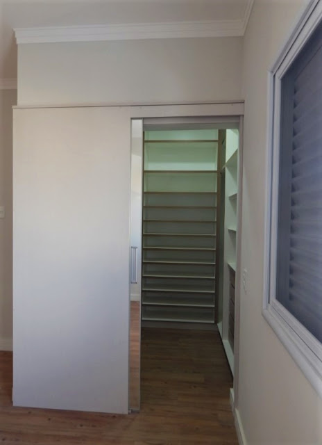 Na suíte principal, uma porta de correr fecha discretamente o closet, que apesar de ocupar pouco espaço, oferece distribuição interna suficiente para guardar os pertences do casal.