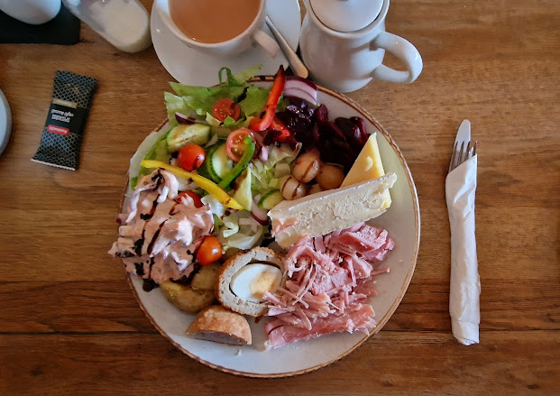 Flatlay - The Potting Shed platter with salad of lettuce, cucumber, tomatoes, onion with dressing. New potatoes. Ham, Cheddar, Brie, Pork Pie, Scotch Egg, freshly made coleslaw and beetroot.