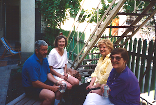 Alex, Mary Ann, Selina, and the ambassador outside the house next door, with the exterior staircase in the background.