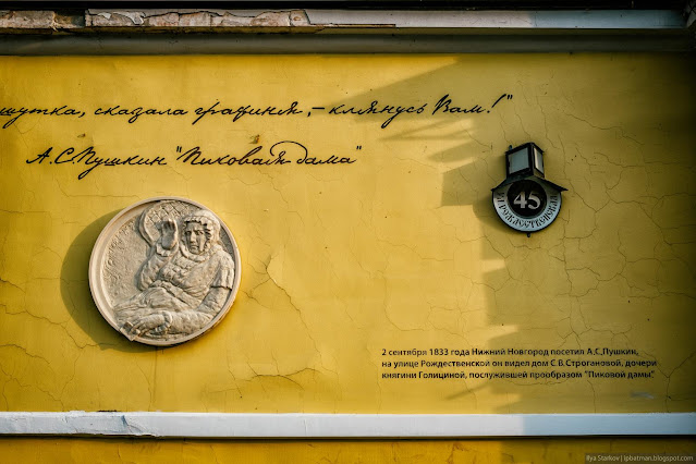 Желтая стена с барельефом женщины и табличкой адресом