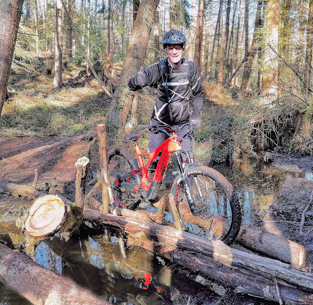 Glenn pushing bike over logs