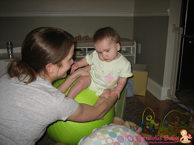 Mom using a stability ball to do strengthening exercise for her baby with torticollis.