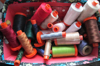 A box of thread with spools of different colors.