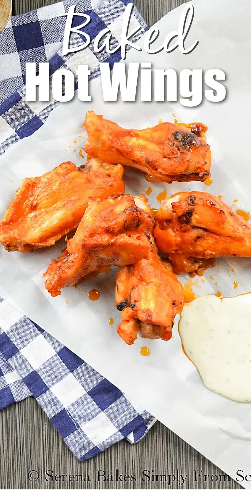 A white plate witch Baked Hot Wings on it with a blue checkered cloth underneath. There is white text at the top Baked Hot Wings.