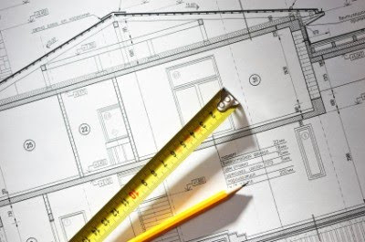 Pencil and tape measure over house plan blueprints