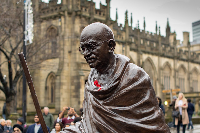 Bronze statue of Gandhi walking with stick in front of cathedral