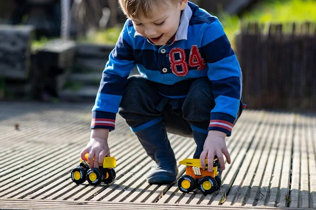 A 3 year old toy playing with small Tonka monster trucks in the garder