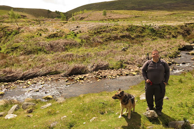 Rich and our dog standing by a shallow stream.