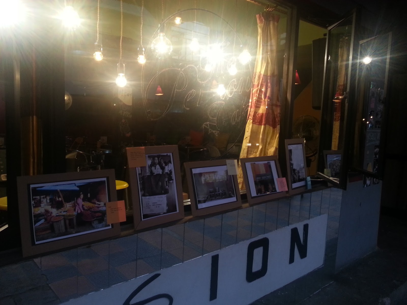 Foto foto pilihan partisipan pameran dipajang dengan pigura di depan cafe pension