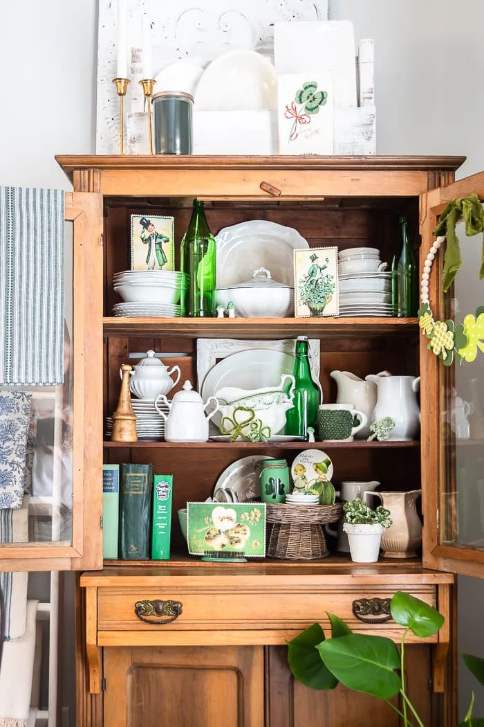 pine cabinet filled with green and white vintage decor