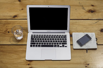 Affiliate marketing work station with a computer, a glass of water and a smartphone on a notepad.