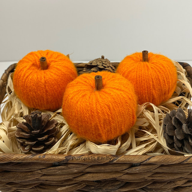 Three orange yarn pumpkins in a basket.