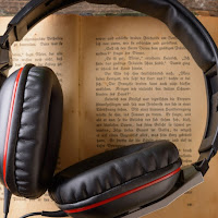 A pair of chunky over-ear headphones rest on an old book.