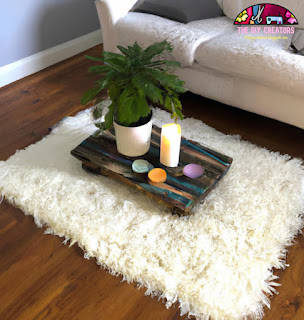 A photo of a macrame hammock chair hanging from the ceiling in a cozy living room setting. The chair is decorated with a patterned cushion and a throw blanket.