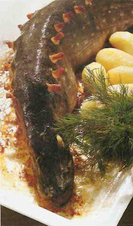 ryba upieczona w całości, naszpikowana boczkiem, na półmisku, obłożona ziemniakami i przystrojona gałązkami kopru