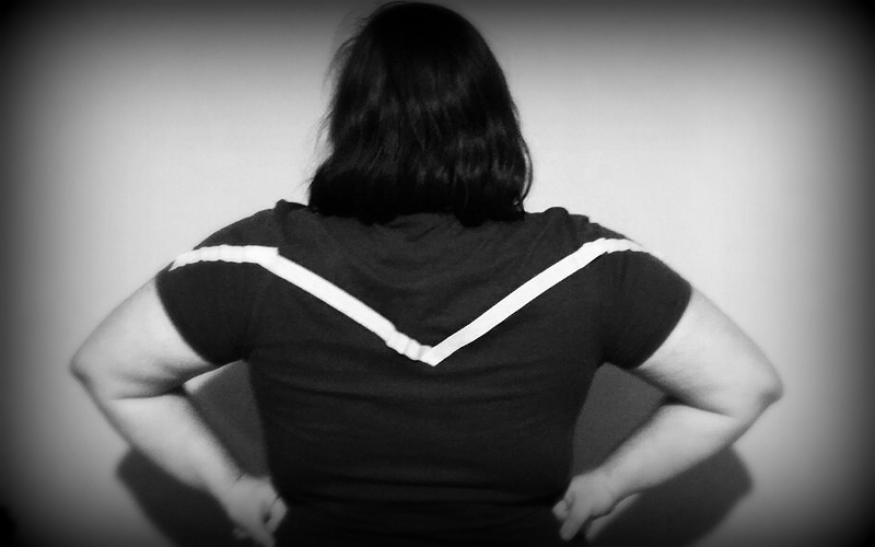 Na imagem: Uma garota de costas com as mãos na cintura