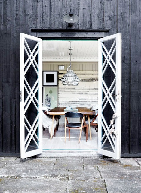 moderndining room with long Danish table, flokati throws on chairs, shell pendant lights, paneled wall texture and french doors with trellis pattern trim woodwork