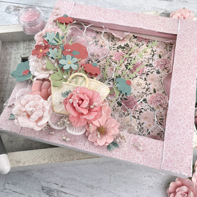 Flower Basket reverse mixed media canvas created with: Sizzix creamy matte paint in cherry blossom, sequin mix in ballet slipper, floral vessels, in the meadow, woodland stems die, muted cardstock, white texture roll; Scrapbook.com cloud whip; Tim Holtz linen distress oxide; Prima miel paper, flowers, art stones