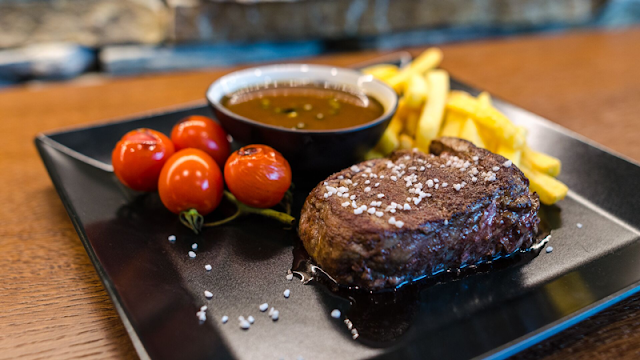 a steak topped with rock salt, with a side of grilled cherry tomatoes