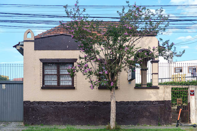 Casa de madeira e com fachada em alvenaria junto à calçada