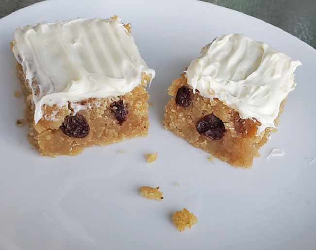 these are spice bars with cream cheese frosting on a white porcelain dish