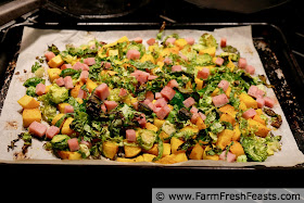 image of baking pan covered with roasted butternut squash cubes, shredded brussels sprouts, and leftover ham cubes