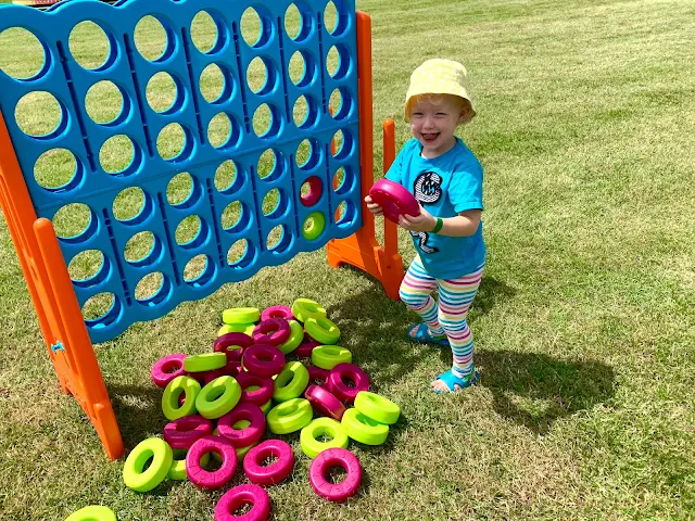 A toddler playing with a large version of connect four