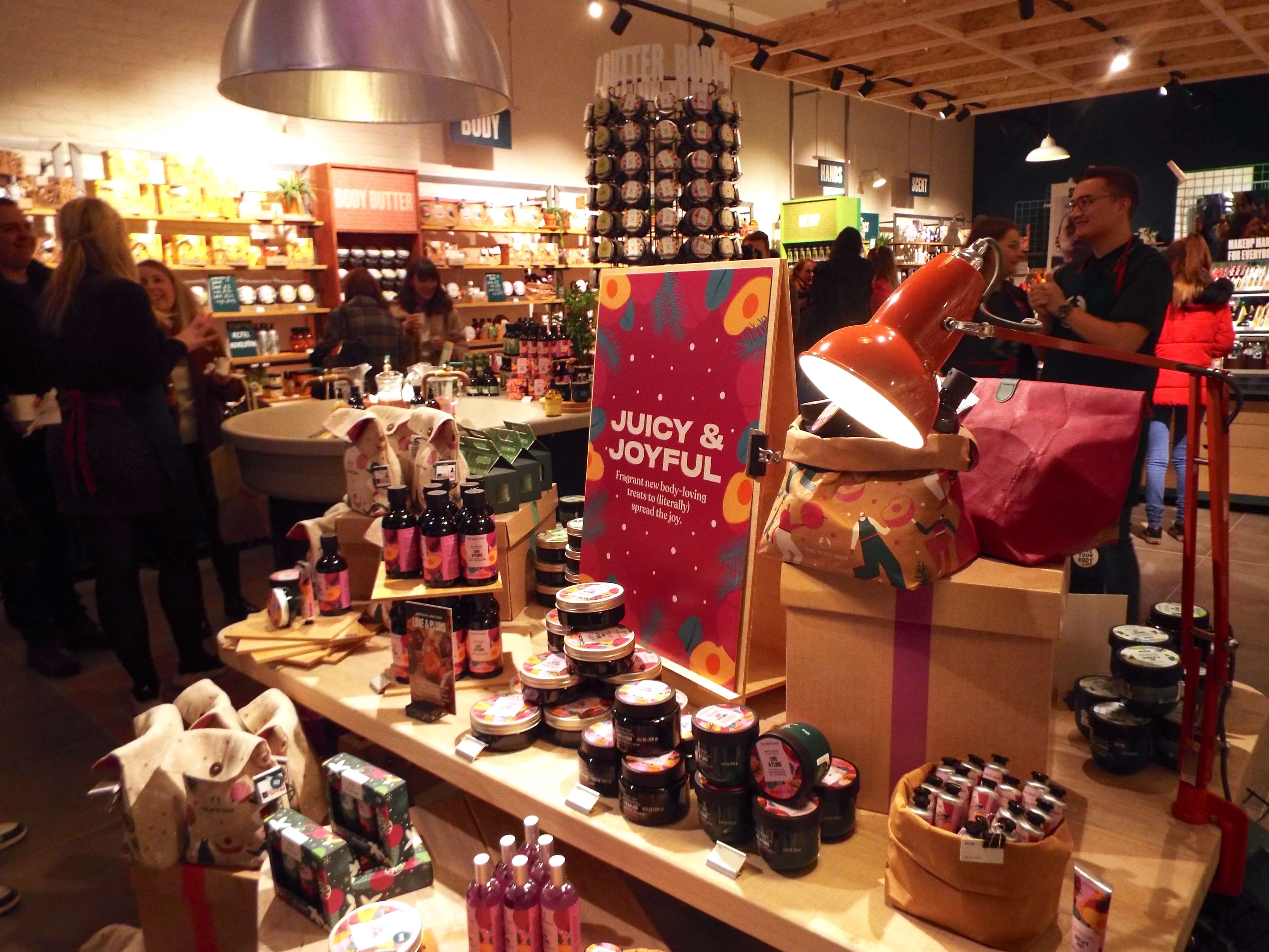 Cascading display of the Christmas Love and Plums range, in the warm glow of the front entrance of the shop, with a sign saying Joyful and juicy to centre.