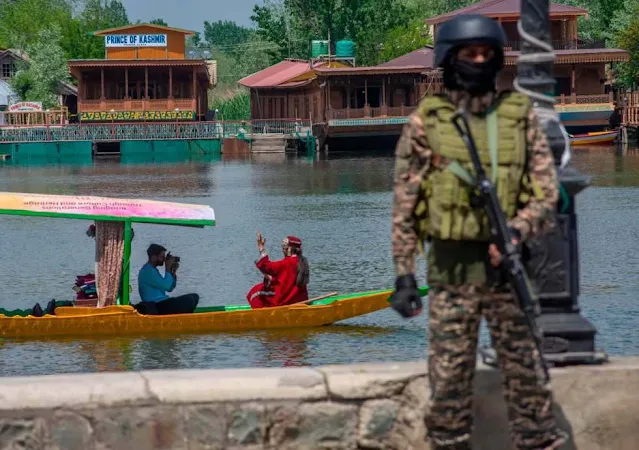 A local Kashmiri photographer captures images of an Indian tourist in a boat as an Indian paramilitary soldier stands guard along the bank of Dal Lake, following an attack on Indian tourists by gunmen on April 24, 2025, in Srinagar, India. Photo by Yawar Nazir/Getty Images