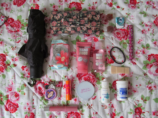 black umberella, hankies, pink floral purse, two pink tubes (hand cream and hand sanitiser), orange lip balm, pink lip crayon, keys, mirror, eye drops, paracetamol, black thin bobble, plaster, pen, chewing gum, sweets