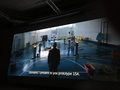 Haapsalu õudukafestival, heltk kinoseansilt. Ekraanil on selja tagant inimfiguur, tema ees täidab spordisaali põrandat mitmesugustest arvutuskomponentidest ja juhtmetest räga.