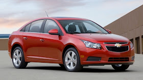 Front 3/4 view of red 2011 Chevrolet Cruze parked on rooftop garage