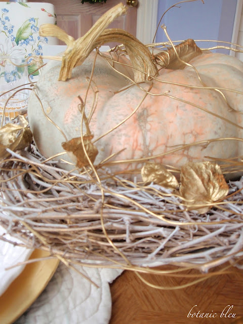 Thanksgiving gold and white table setting with cinderella pumpkin on a white and gold vine base