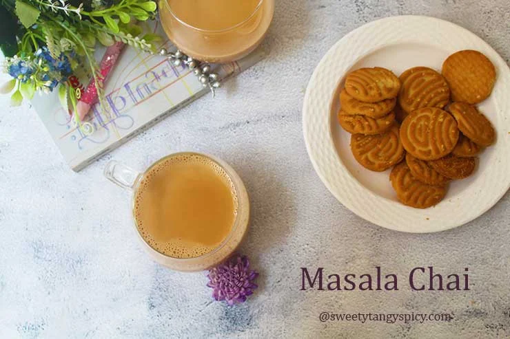 Two cups of masala chai, one half-full and the other full, accompanied by buttery cookies for a cozy and delightful tea experience.