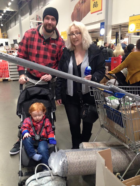 A man, woman and a child in a pushchair with a trolley full of ikea products