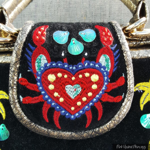 embroidered crab on flap of black handbag