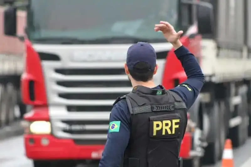 Agente da PRF dando ordem para caminhão Scania vermelho