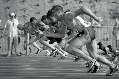 athletes-running-on-track-and-field-oval-in-grayscale