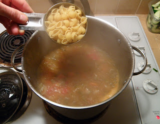 Hand Adding Measured Pasta to Boiling Soup