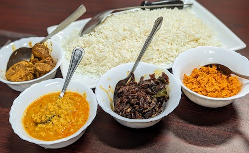 Sri Lankan traditional plate with white rice, lentil curry, coconut sambal, chicken curry, and tempered sprats