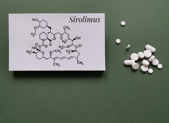 Imagen de la fórmula química estructural de la molécula de sirolimus (rapamicina) con tabletas y píldoras blancas.