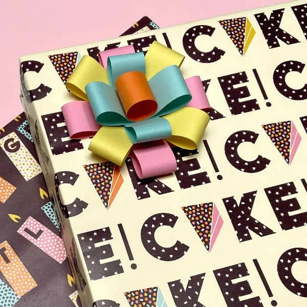 wrapped gift with cake slice and cake lettering paper design with multi-color bow on top