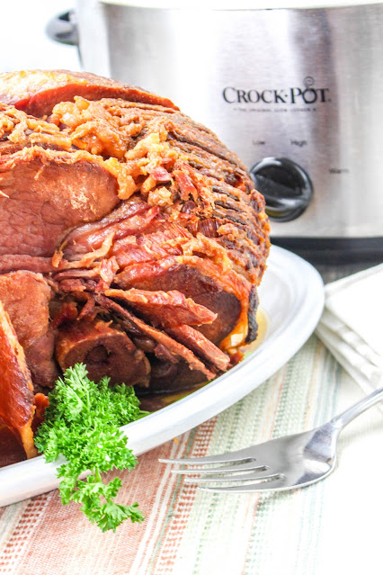 whole ham on a white platter with parsley garnish.