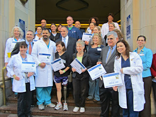 A group photo of me with my medical team and family, standing on the hospital steps, holding signs that says "Mile 160."