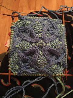 Same square in progress on double-pointed needles. The cables are looking almost floral now.