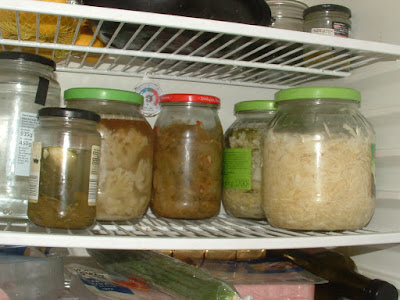 Several jars of fermented vegetables on a fridge shelf