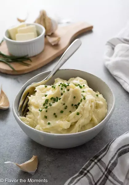 Side view of instant pot garlic mashed potatoes in a white bowl.